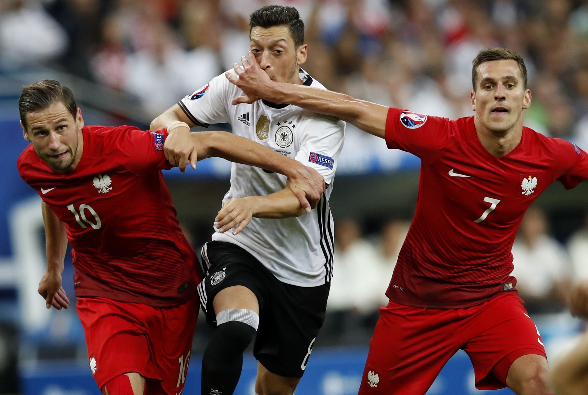 Germany's Mesut Ozil, center, is challenged by Poland's Grzegorz Krychowiak, left, and Poland's Arkadiusz Milik during the Euro 2016 Group C soccer match. (AP Photo)