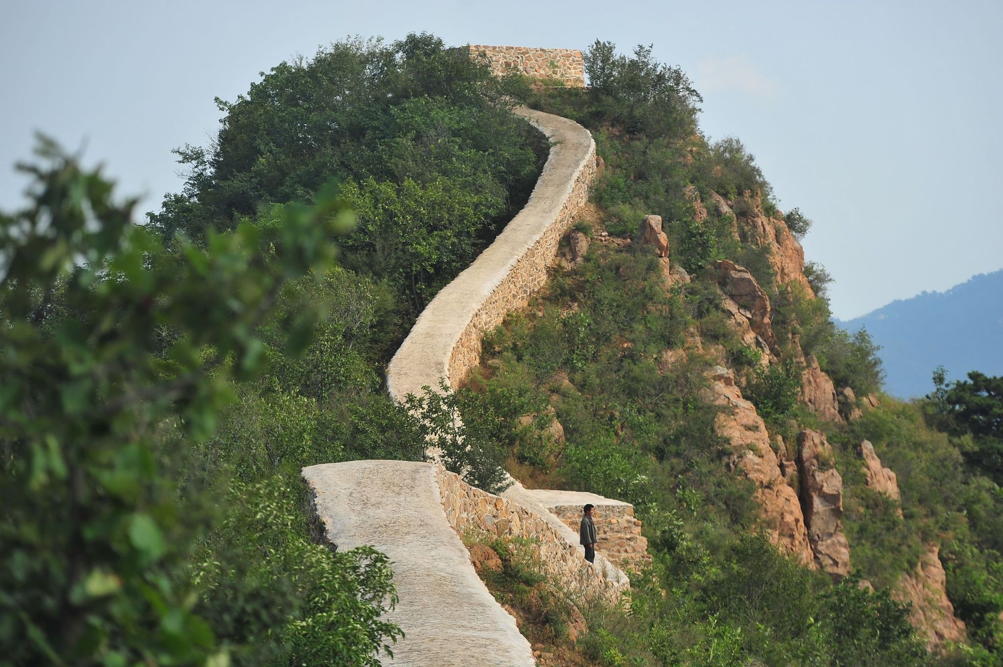 This picture taken on September 21, 2016 shows a villager walking on a paved-over section of the Great Wall of China at Suizhong, in China's northeast Liaoning province. (AFP Photo)