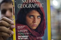 Pakistan's Inam Khan, owner of a book shop shows a copy of a magazine with the photograph of Afghan refugee woman Sharbat Gulla,Wednesday, Oct. 26, 2016. (AP Photo)