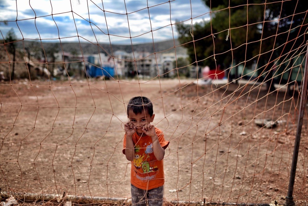 A boy looks from behind a net at the refugee camp of Schisto on June 8. (AFP Photo)