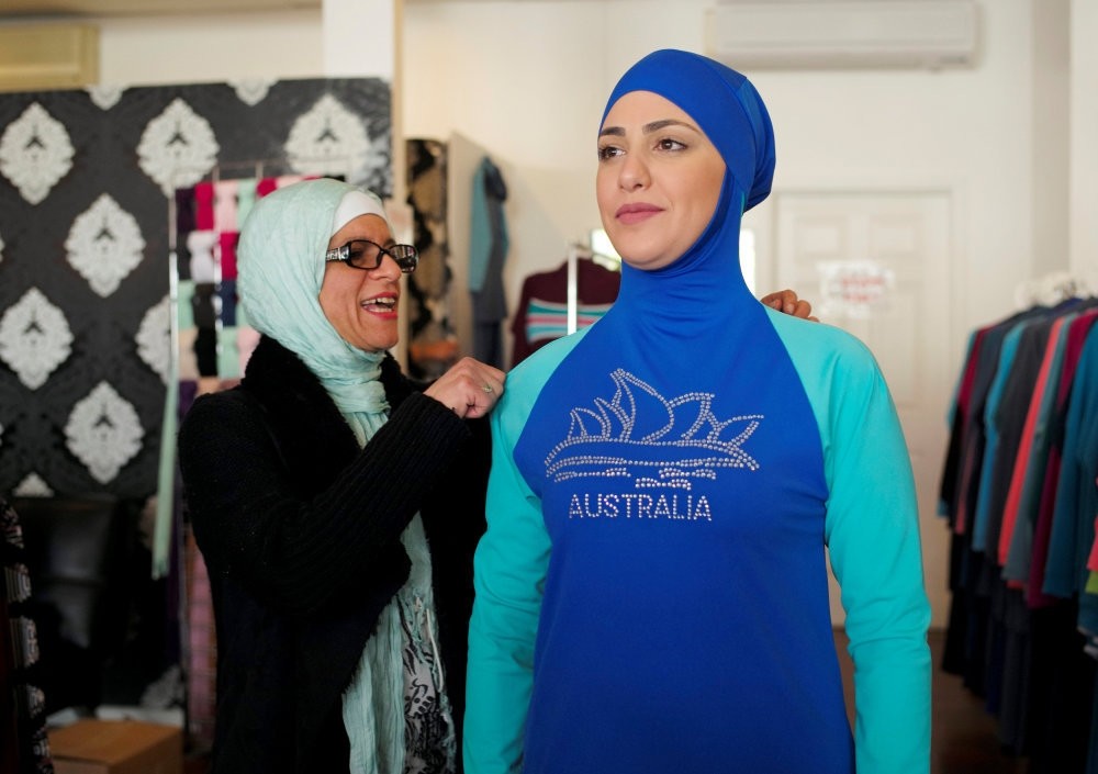 Aheda Zanetti (L), designer of the burkini swimsuit, adjusts one of the swimsuits on a model at her fashion store in Sydney.