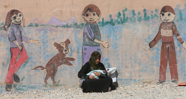 A displaced woman, who fled from Daesh terrorists in Mosul, holding her baby at Deepaka camp in the northwest of Irbil, during an operation against Daesh in Mosul, Iraq, Oct. 20, 2016.