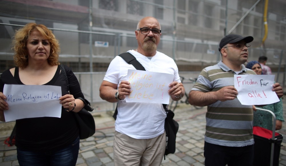 Refugees from Syria and Iraq stand near the site of the attack and hold up signs reading ,Peace for all, and ,My religion is love,, Ansbach, Germany, July 26.
