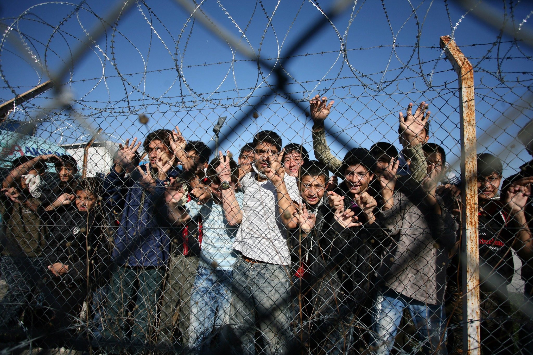 Immigrant minors peer out through the fence of an immigrant detention center in the village of Filakio, on the Greek-Turkish border. (AFP Photo)