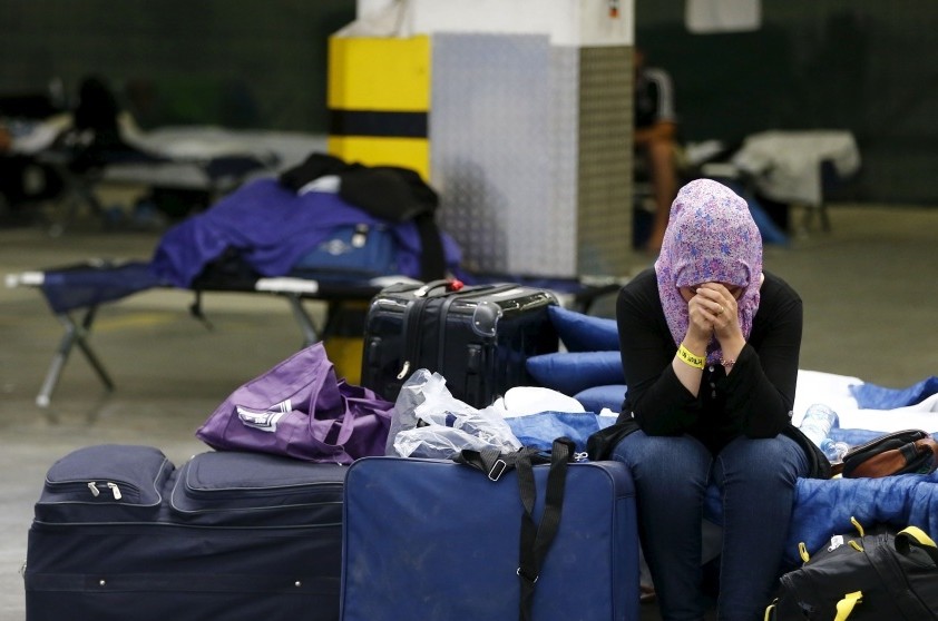 A Syrian sits on a folding bed in a former newspaper printing house being used as a refugee registration center in Frankfurt.