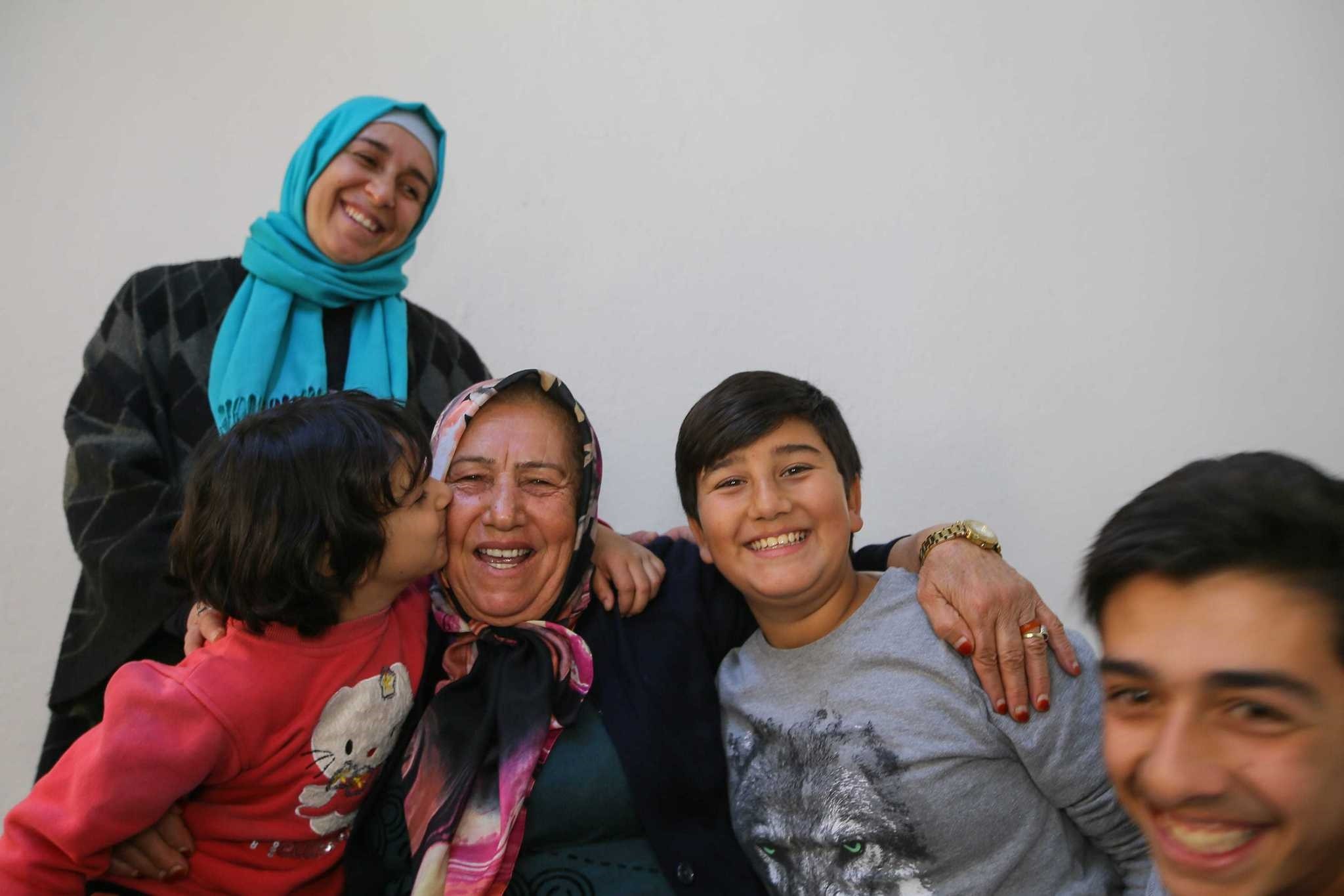 Children of the Syrian family embrace and kiss Nabiha Acar who has helped them since they settled in u0130zmir.