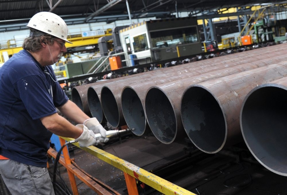 An employee checks a steel pipe in the manufacturing hall at Vallourec and Mannesmann in Duesseldorf, Germany.