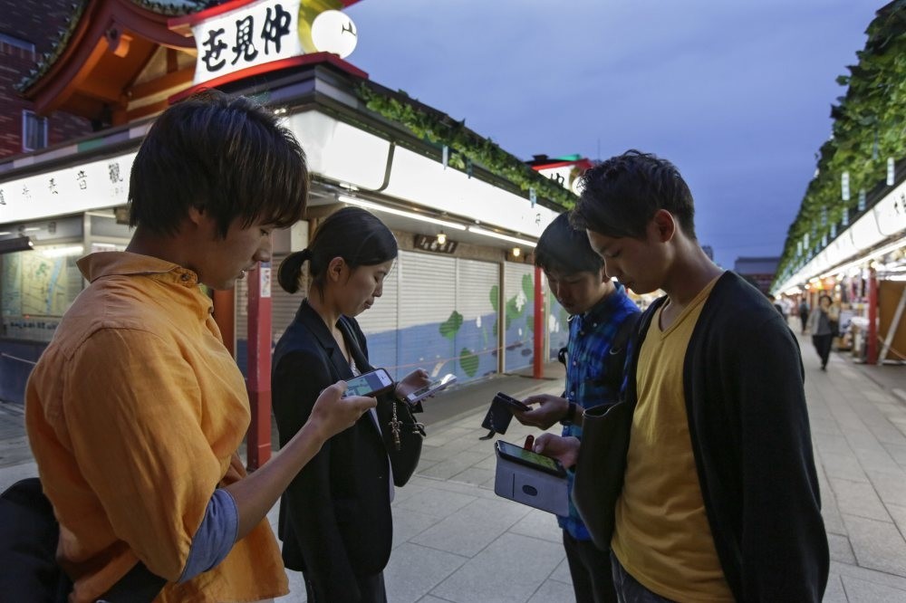 Japanese university students enjoy playing Nintendo's hit mobile game Pokemon Go at Nakamise Street at Sensoji Temple, in Tokyo downtown Asakura district, Japan, on July 22. (EPA Photo)