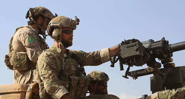 Armed men wearing YPG uniform identified by Syrian Democratic forces as US special operations ride in the back of a pickup truck in the village of Fatisah in the northern Syrian province of Raqqa on May 25, 2016. (AFP Photo)