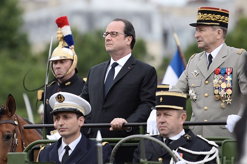 French President Francois Hollande, left, and Chief of Staff French army Gen. Pierre de Villiers arrive in a command car for the annual Bastille Day military parade on the Champs Elysees avenue in Paris, France. July 14, 2016. (AP Photo)
