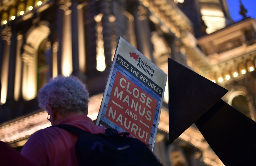 A man with a placard in protest of Australia's immigration policy during a candlelight vigil in Sydney on April 30 for an Iranian refugee who died three days after he set fire to himself on the remote Pacific island of Nauru.