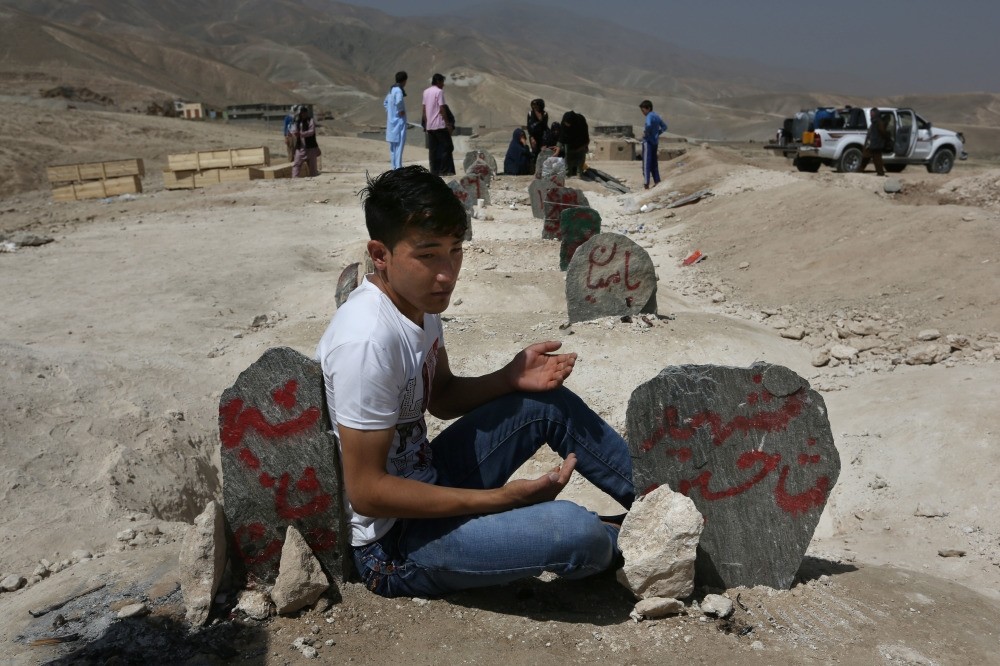 A man prays in front of graves of victims of a suicide attack, Kabul, July 25.
