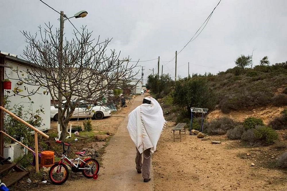 A Jewish settler covered in a prayer shawl walks back to his house in Amona, an unauthorized Israeli outpost in the West Bank.