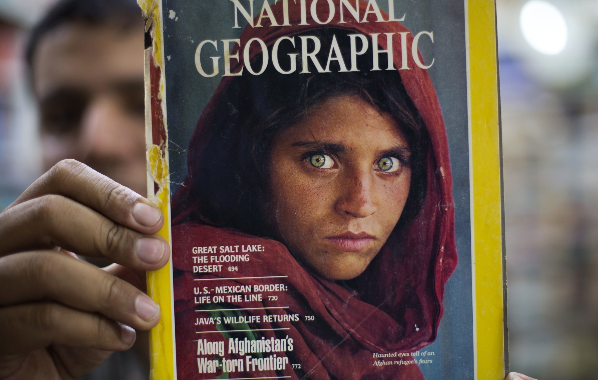 Pakistan's Inam Khan, owner of a book shop shows a copy of a magazine with the photograph of Afghan refugee woman Sharbat Gulla,Wednesday, Oct. 26, 2016. (AP Photo)