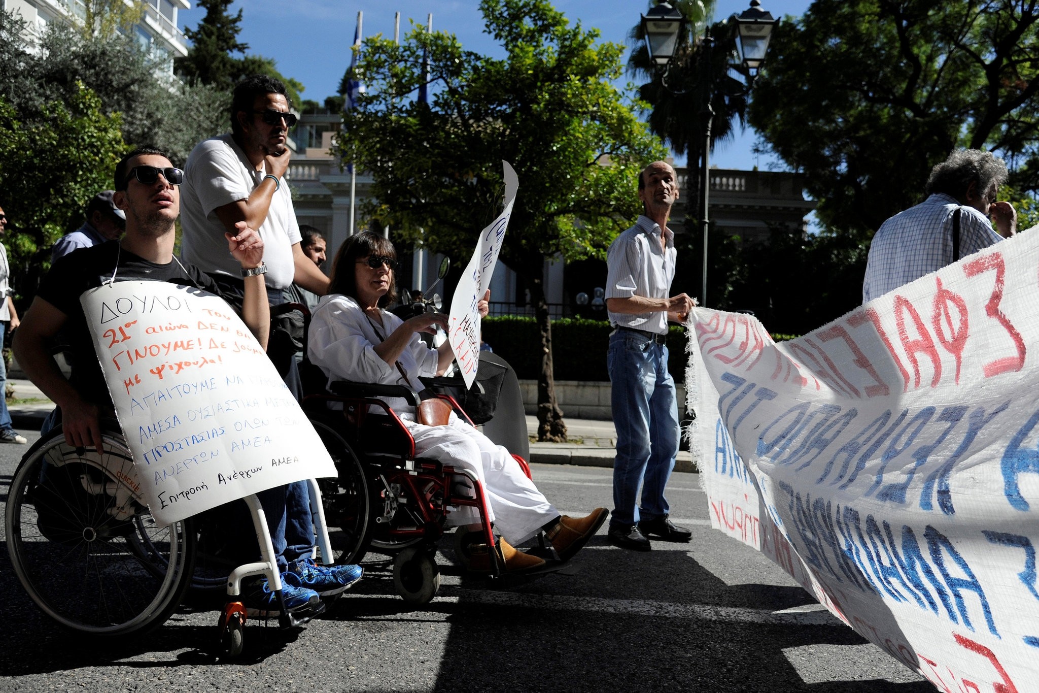 Greek demonstrators with physical disabilities protest outside the Maximos Mansion calling on the government not to cut down their monthly disability subsidy and pension. (REUTERS Photo)