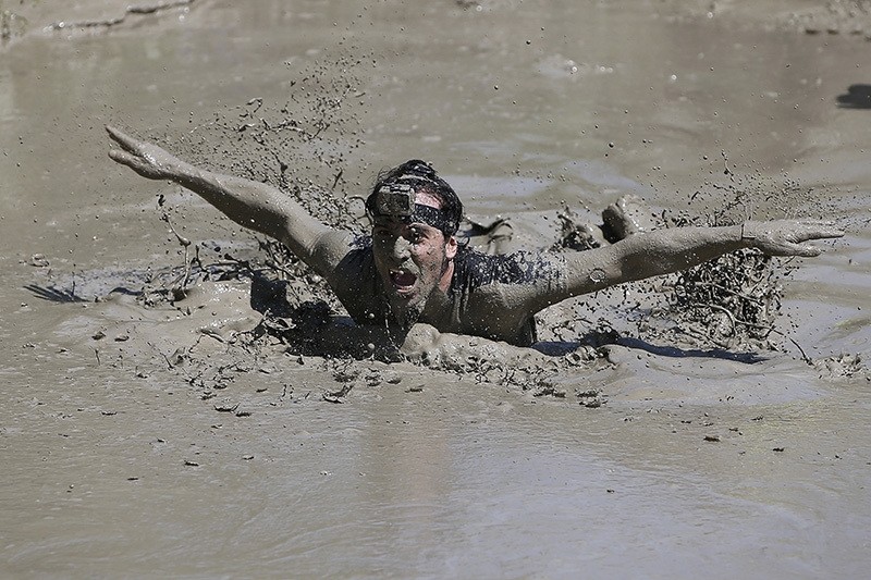 A participant swims to cross a mud pool during the Mud Day athletic event at El Goloso Military base on the outskirts of Madrid, Spain, Saturday, June 11, 2016. (AP Photo)