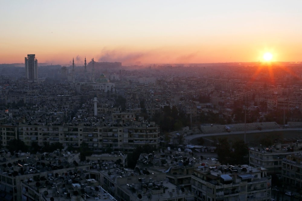 The sun rising with smoke billowing in the air near Aleppo's historic citadel, as seen from a regime-controlled area of Aleppo, Syria, Dec. 6, 2016.