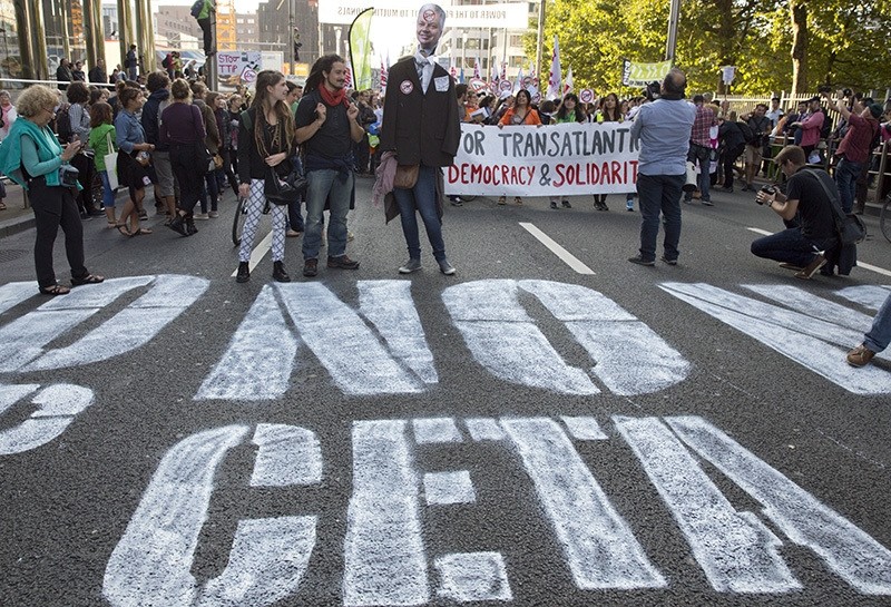 In this photo taken on Tuesday, Sept. 20, 2016, demonstrators walk over a spray painted sign on the street during a demonstration against international trade agreements in Brussels. (AP Photo)