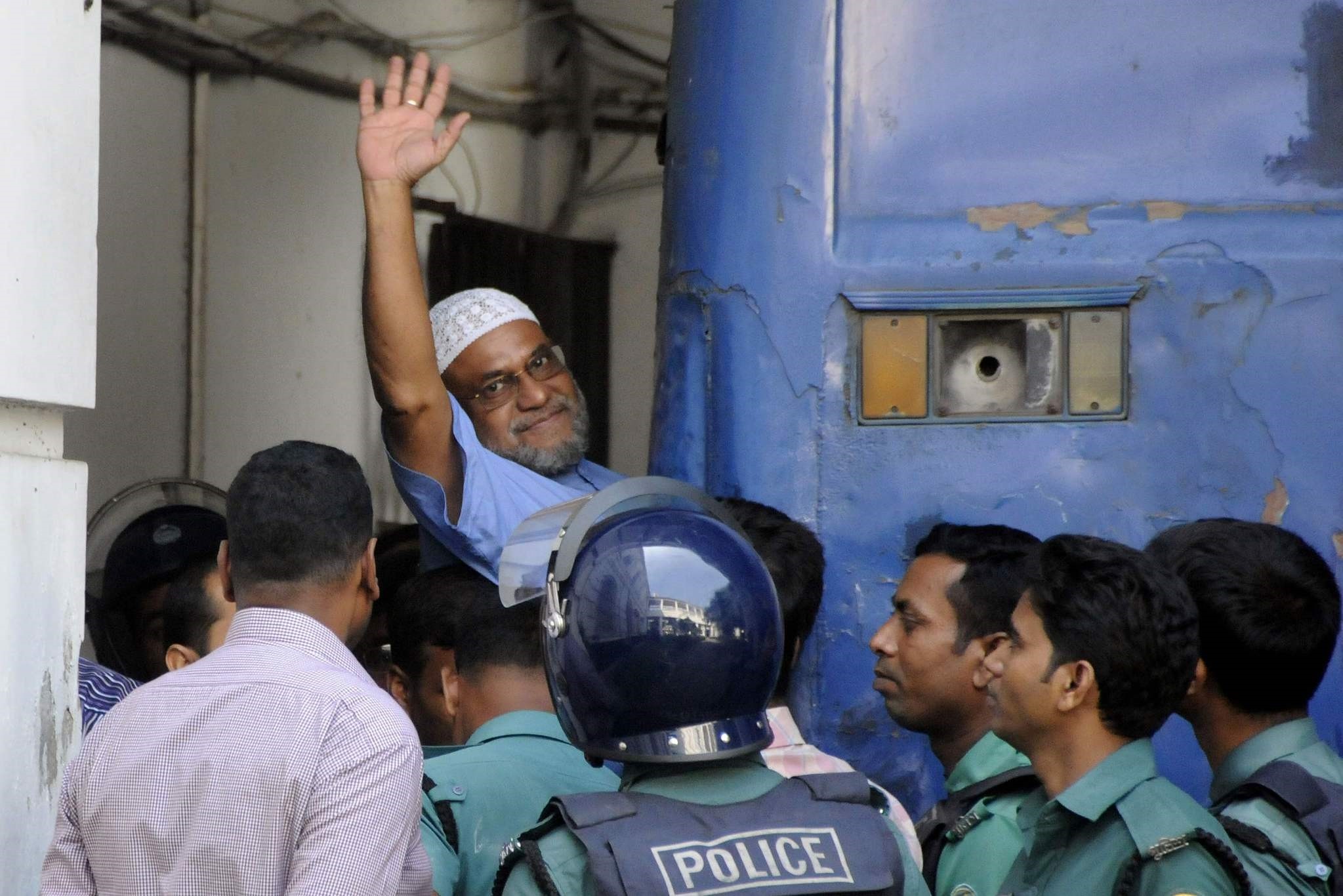 This file photograph taken on November 2, 2014, shows Bangladeshi Jamaat-e-Islami party leader, Mir Quasem Ali waving as he enters a van at the International Crimes Tribunal court in Dhaka. (AFP Photo) 