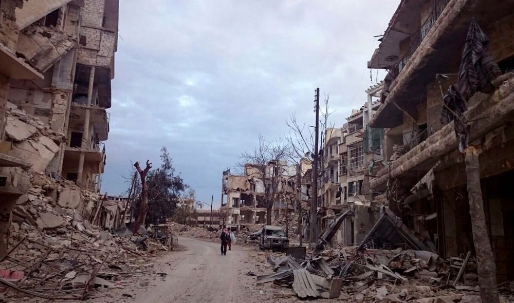Men walk past damaged buildings and shops in the eastern Aleppo neighborhood of al-Mashhad, Syria, Dec. 8.