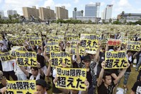Protesters hold placards that read: ,Our anger has reached its limit, during a protest rally against the presence of U.S. military bases.