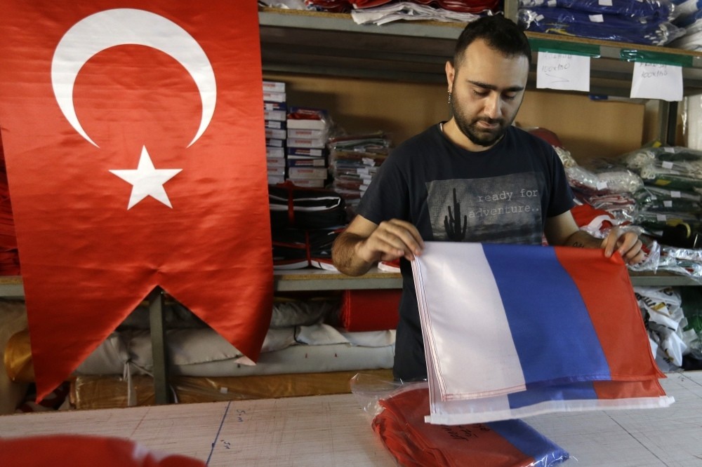 An employee of a flag-making factory folds a Russian flag as a Turkish flag adorns the display at left, in Istanbul, Aug. 9.