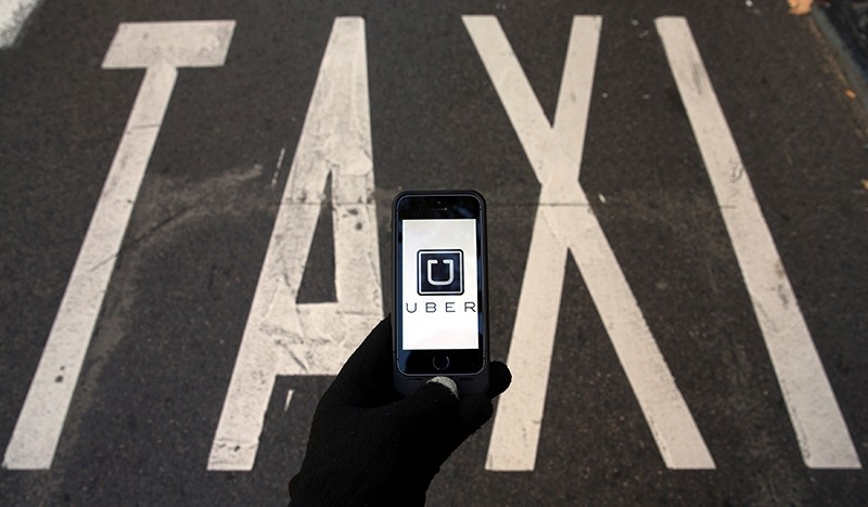 The logo of car-sharing service app Uber on a smartphone over a reserved lane for taxis in a street is seen in this photo illustration taken in Madrid on December 10, 2014 (Reuters Photo)