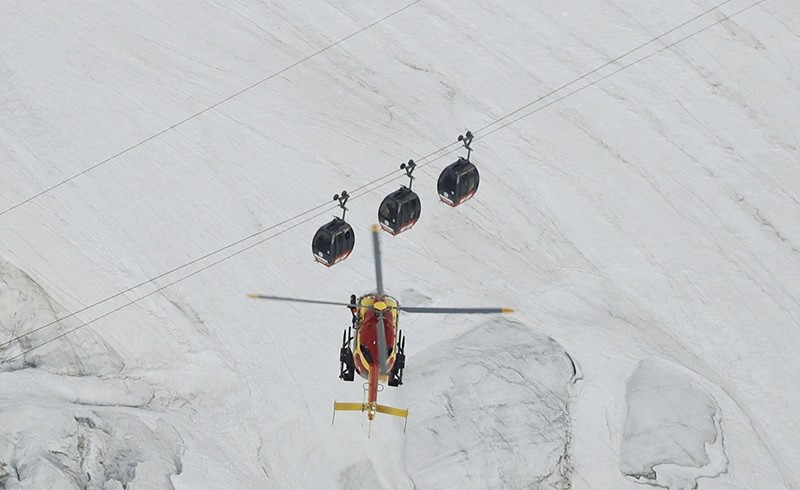 An EC-135 helicopter operated by the French Societe' Civile hovers, Friday, Sept. 9, 2016, near three cars of the Panoramic Mont Blanc cable car (AP Photo)