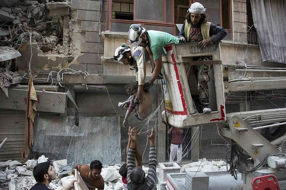 Syrian rescuers hand the body of a girl down to civilians on the ground after she was pulled from the rubble of a bundling following Assad forces airstrikes in the opposition-held neighborhood of Al-Shaar in Aleppo on Sept. 27.