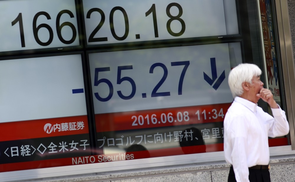 A man stands near an electronic stock board showing Japanu2019s Nikkei 225 index at a securities firm in Tokyo.