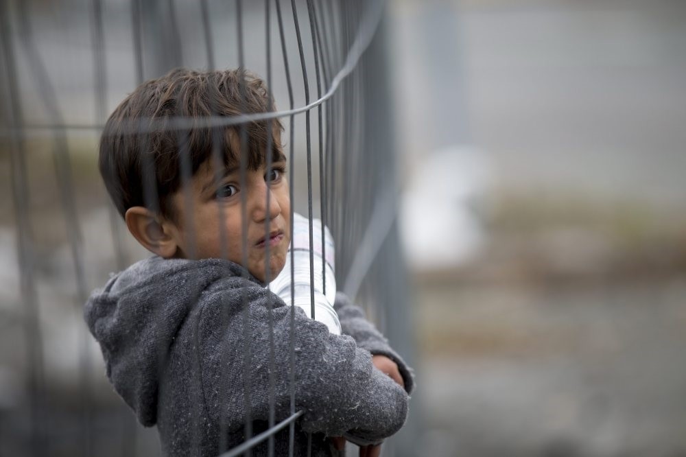 A refugee child looks through a fence in one of the alleys of the al-Kallasseh area in the eastern neighborhoods of Aleppo, Syria, Dec. 30, 2016.