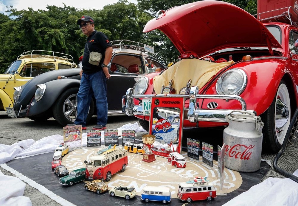 A man walks along different Volkswagen Beetles and collectible toys during the World Volkswagen Day in Quezon city, east of Manila, Philippines.