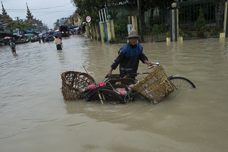 A man pushes his trishaw through the water after seasonal flooding hit the city of Pathein in the Irrawaddy region on August 13, 2016. (AFP Photo)