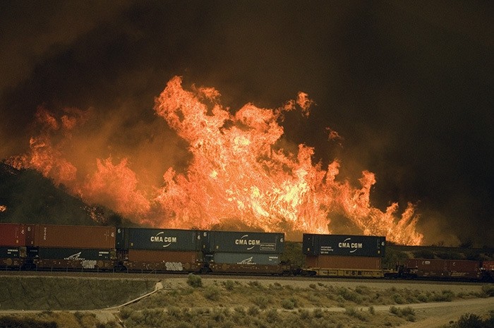 Flames erupt on a hillside alongside one of the main rail routes connecting Southern California with points north and east as a wildfire rages out of control in Cajon Pass north of Devore, Calif., Tuesday, Aug. 16, 2016. (AP Photo)