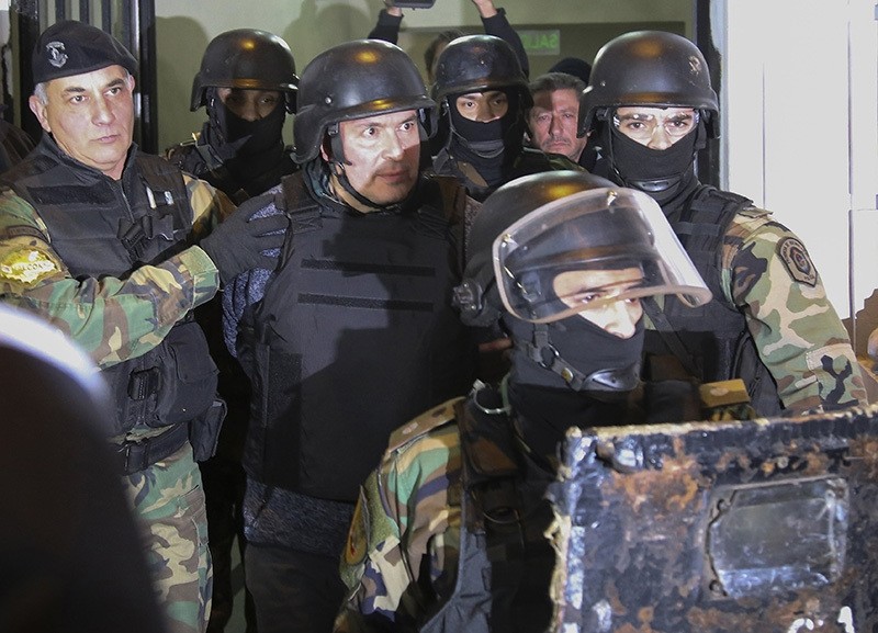 Jose Lopez (C) is taken into custody after being arrested in General Rodriguez, province of Buenos Aires on June 14, 2016 while he was trying to hide 160 packages with more than eight million dollars in the garden of a nunnery. (AFP Photo)