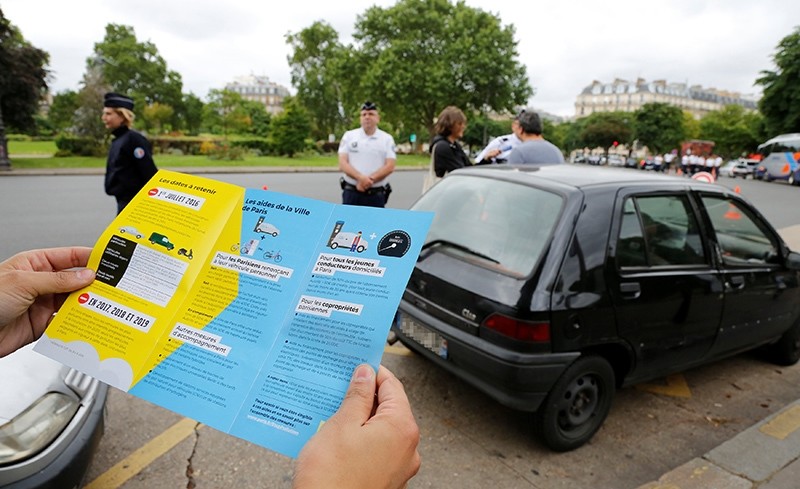 A man holds a leaflets as French police speaks to a driver with a car older than 20 years to explain a new law to fight air pollution at the Place de la Nation square in Paris, France, July 1, 2016 (Reuters Photo)