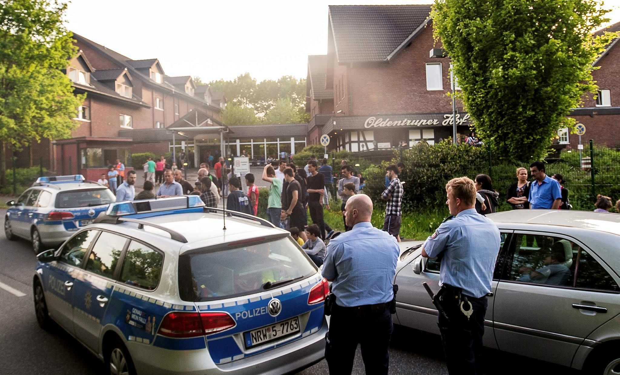  police and refugees stand near a refugee shelter in Bielefeld, Germany. (AP Photo)