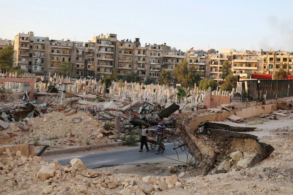 People walk near an over-crowded graveyard in the opposition-held al-Shaar neighborhood of Aleppo, Syria Oct. 6.