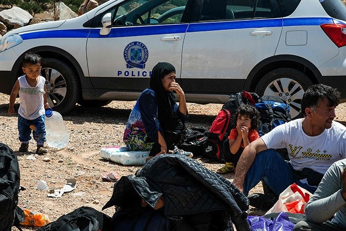 Refugees and migrants sit on the ground by a Greek police car upon their arrival with a boat near the village of Finokalia in the southern Greek island of Crete on May 31, 2016. (AFP Photo)