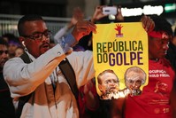 A demonstrator set fire to a poster that reads: ,Coup Republic,, during a protest in support of Brazil's suspended President Rousseff.