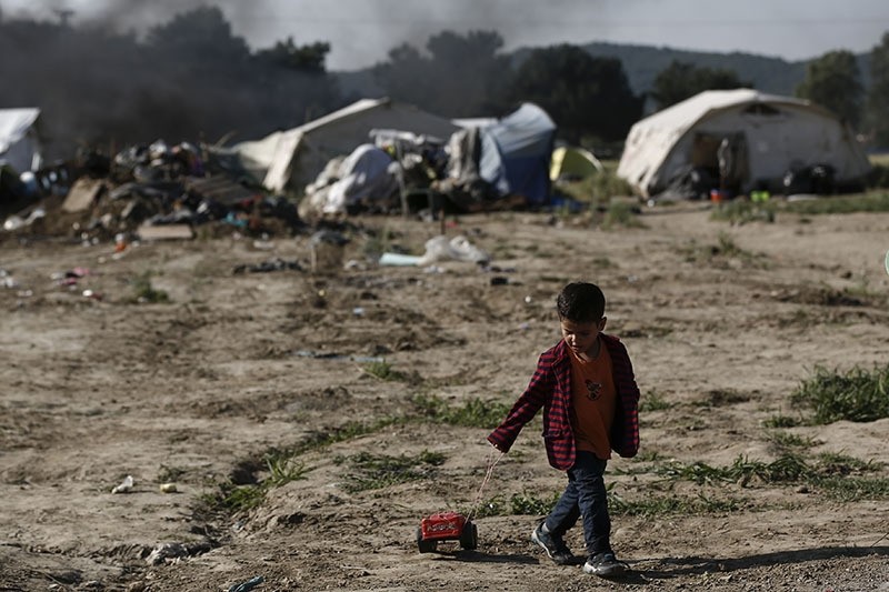 Boy pulls a toy as he and his family leave the makeshift camp during police operation at the Greek-Macedonian border near northern Greek village of Idomeni (AP)