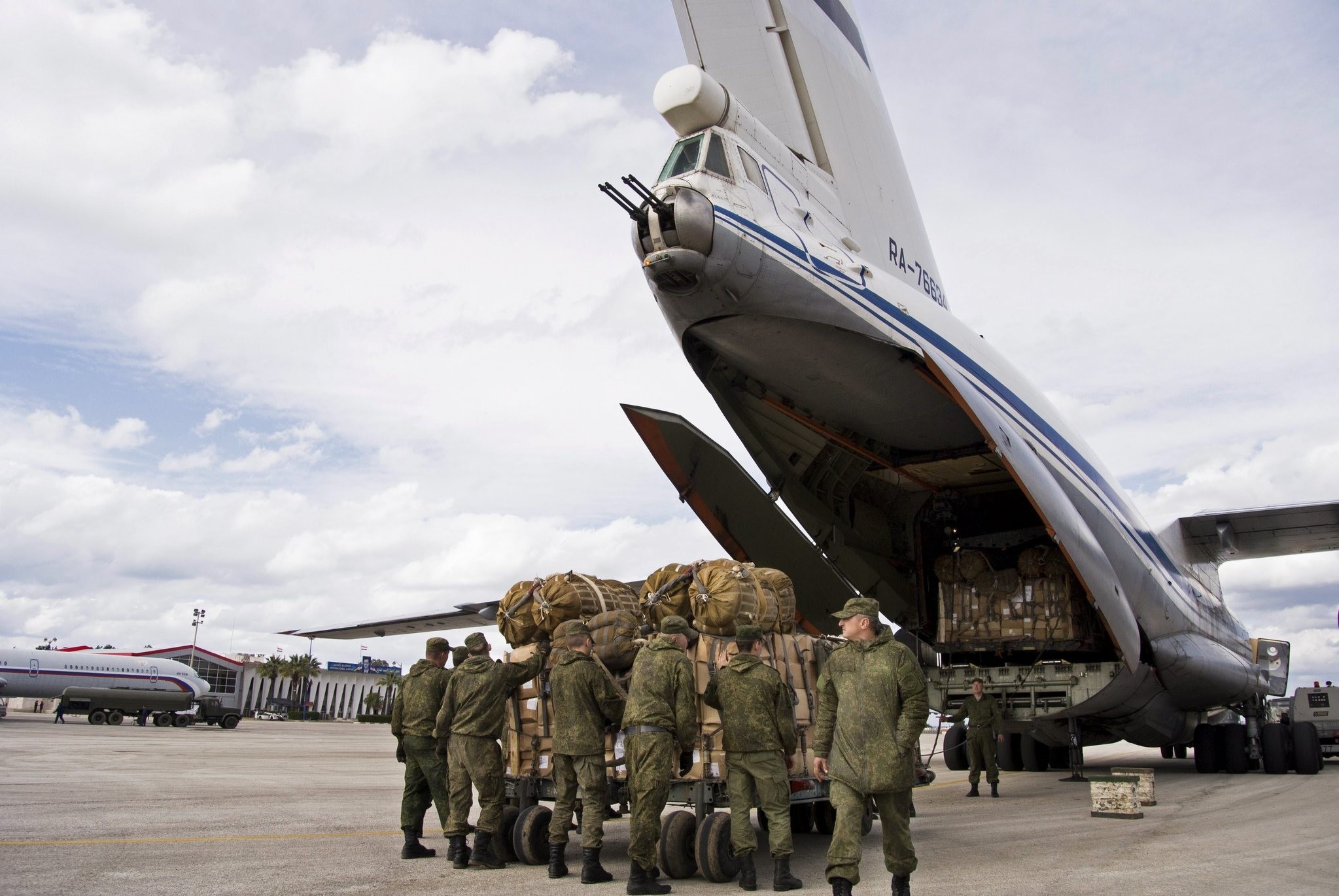 Russian air force personnel prepare to load humanitarian cargo on board a Syrian Il-76 plane at Hemeimeem air base in Syria. ((AP Photo)
