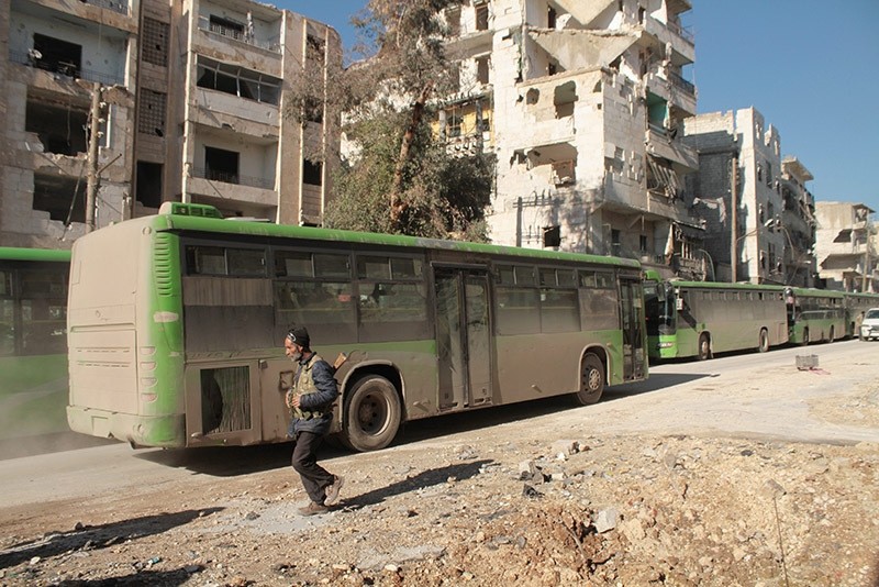  An armed man walks next to evacuation buses, Aleppo, Syria. (EPA Photo)
