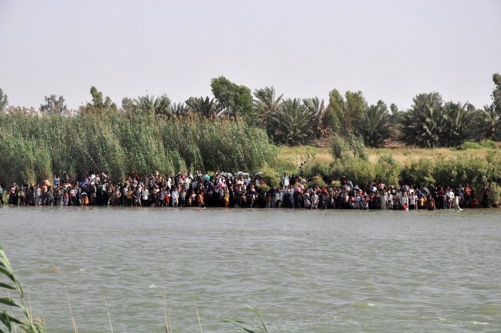 Internally displaced civilians from Fallujah flee their homes, gathering on the edge to cross the Euphrates River.