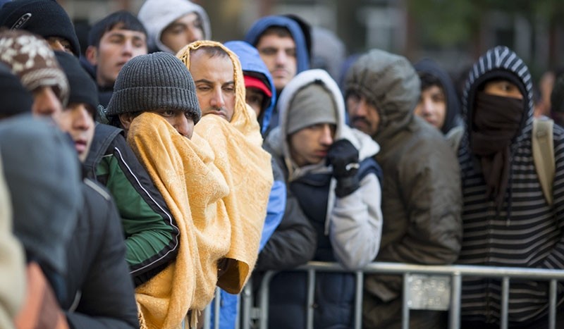 Refugees, migrants try to keep warm as they wait for registration and allocation of a sleeping place on the premises of the State Office of Health and Welfare in Berlin, Germany, 12 October 2015. (EPA Photo)