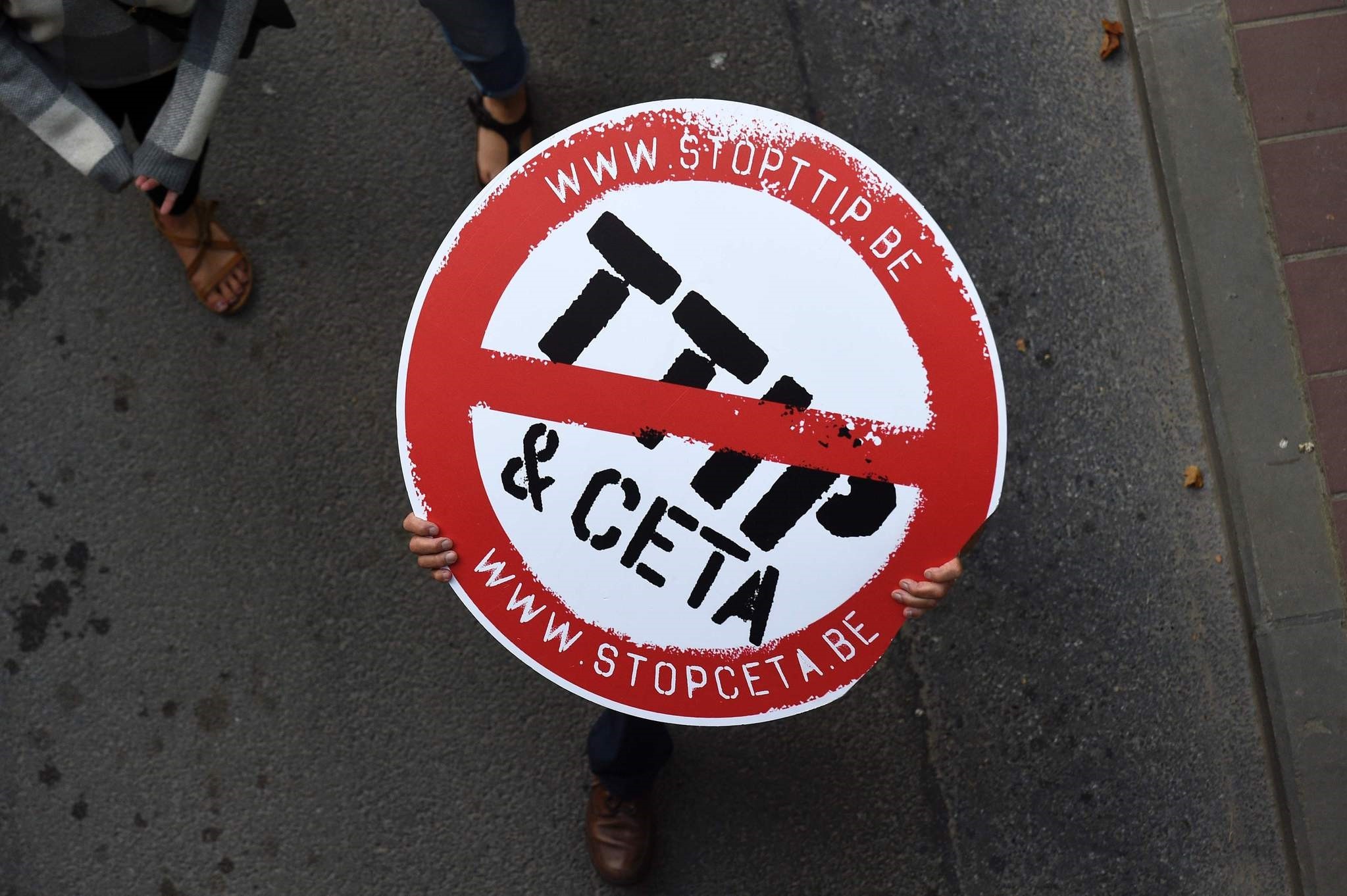 A man holding a no entry sign with the TTIP and CETA logos during a demonstration in Brussels. (AFP Photo)