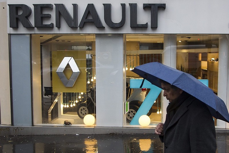 This file photo dated Dec. 14, 2012 showing a pedestrian with an umbrella in front of a Renault dealership in Paris, France. (EPA Photo)