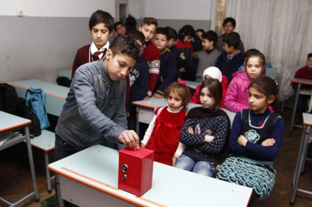Young Syrian students putting their savings in a donation box in their classroom. Syrians in Turkey are concerned about well-being of their relatives and friends in Aleppo.