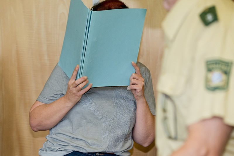 Defendant Andrea G. , who is accused of murder, covering her face with a folder, in the court room of the regional court in Coburg, Germany, Tuesday July 12, 2016. (AP Photo)