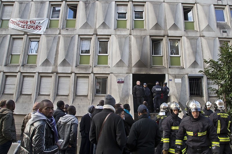 Migrants and fire fighters gather outside a migrant workers' center after a fire broke out in Bouglogne-Billancourt, west of Paris, Friday, Dec. 16, 2016. (AP Photo)